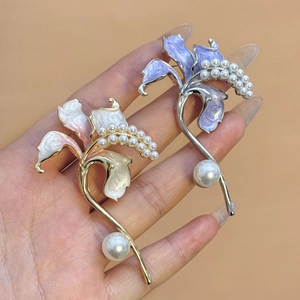 Vista macro di eleganti spille a giglio con petali smaltati e decorazioni di perle