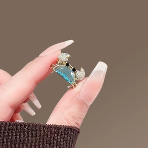 Exquise broche crabe dorée avec corps en pierre bleue ciel et détails en zircon blanc