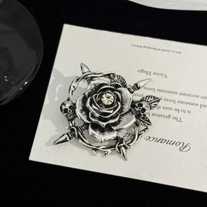 Détail d'une broche gothique avec crâne et rose sertie de cristaux sur velours noir