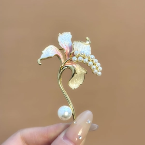 Dettaglio di un'elegante spilla a fiore di giglio in smalto rosa con perle