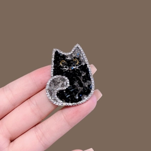 Détail d'une broche chat sertie de cristaux noirs et argentés avec yeux ambrés