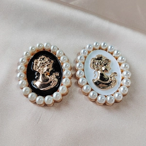 Macro detail of oval vintage cameo brooches with gold relief portraits and pearl borders
