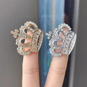 Détail de la broche couronne avec strass blancs en placage or et argent sur le doigt