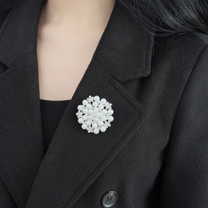 Close-up of pearl and rhinestone sunflower brooch pinned on a black wool blazer lapel