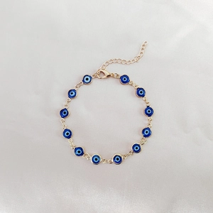 Dettaglio del bracciale Evil Eye dorato con ciondoli in smalto blu e chiusura regolabile