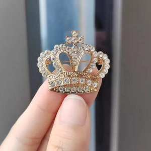 Vue détaillée d'une broche couronne dorée avec strass scintillants et pointe de croix