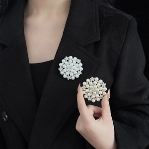 Elegant sunburst pearl brooch with rhinestones worn on black wool coat for women