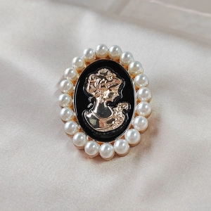 Macro detail of vintage cameo brooch with golden alloy relief and white pearls