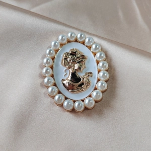 Vintage oval cameo brooch with golden lady portrait and elegant pearl border on silk background