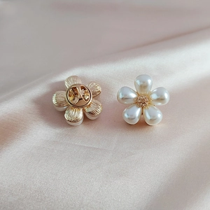 Elegant pearl daisy brooch with gold metal base and diamond center on silk fabric