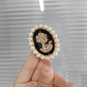 Close-up of vintage relief brooch with golden female profile and faux pearl border