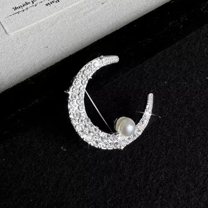 Elegant silver crescent moon brooch with shimmering crystals and a white pearl accent