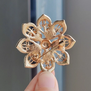 Golden eight-petal flower brooch with crystal pearls showing secure pin clasp back
