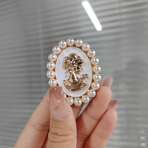 Macro shot of vintage gold lady cameo brooch with white pearl oval border detail