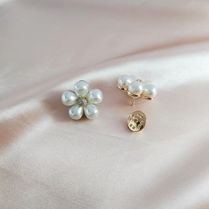 Elegant pearl daisy brooch with golden petals and rhinestone center on silk background