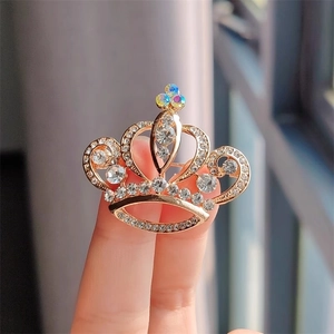 Vue macro de la broche couronne dorée avec incrustation de cristaux multicolores