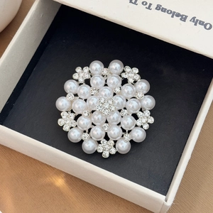 Detail shot of elegant floral pearl brooch with rhinestones in a black velvet jewelry box