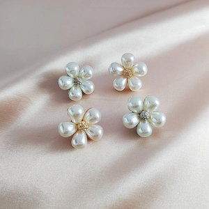 Detailed close-up of pearl flower brooches with crystals on a luxury silk background