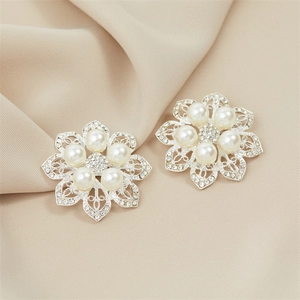 Detail of flower brooch with delicate silver filigree petals and white pearls on satin