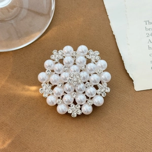 Detailed top view of a sunflower pearl brooch with sparkling rhinestones and silver setting