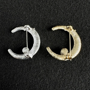 Detail view of gold and silver moon brooch backings with pearl and textured finish