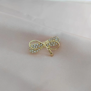 Detail of a golden bow brooch inlaid with clear rhinestones on pink silk fabric