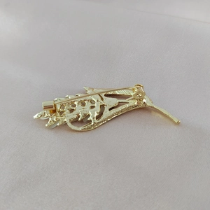 Vue arrière de la broche épi dorée avec fermoir sécurisé sur tissu en soie beige