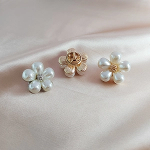 Detailed view of pearl daisy brooches with gold finish and pin backing on silk