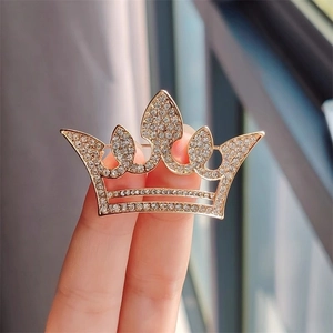 Détail macro de la broche couronne dorée sertie de strass blancs sous une lumière naturelle