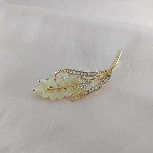 Élégante broche épi de blé dorée avec pierres d'opale et strass brillants sur soie rose