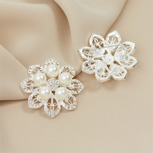 Elegant silver flower brooch with white crystal pearls and rhinestones on silk fabric