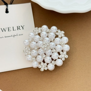 Detailed view of elegant pearl and rhinestone floral brooch on jewelry display card