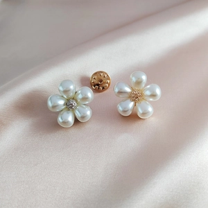 Detailed close-up of white pearl flower brooch pins on elegant pink silk fabric background