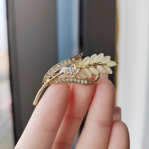 Broche blé dorée élégante avec pierres œil de chat et strass brillants en main
