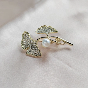 Detailansicht der goldenen Ginkgo-Brosche mit weißen Kristallen und runder Perle
