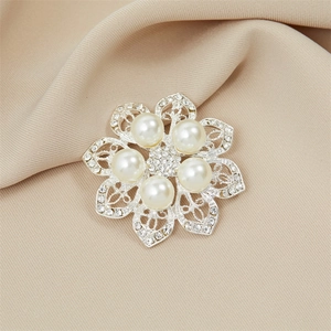 Detail of flower brooch with crystal pearls and silver petals on beige silk fabric