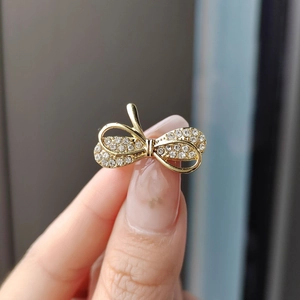 Elegant gold bow brooch with shimmering rhinestones held to show the realistic size