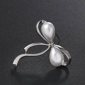 Elegante broche de lazo con perlas de gota y diamantes sobre un fondo negro