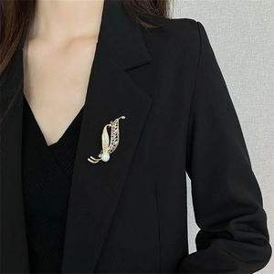 Elegant gold leaf brooch with crystals and pearl on a black suit lapel