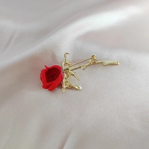 Élégante broche rose rouge avec placage doré et finition émail sur fond de soie blanche