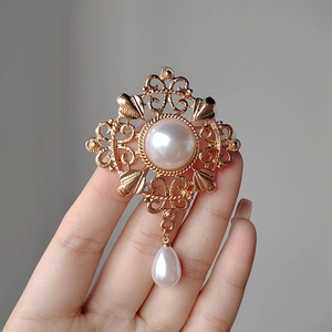 Detail of vintage gold hollow brooch with large pearl and hanging teardrop pearl charm