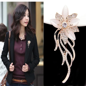 Detail of flower brooch with pink cat eye stone petals and crystal inlaid leaves
