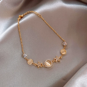 Elegante gouden armband met kattenoogstenen en fonkelende sterren op zijden achtergrond