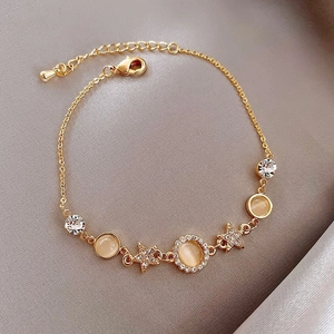 Elegante gouden sterarmband met kattenoogstenen en kristallen op zijden stof