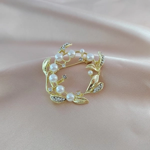Elegant vintage pearl wreath brooch with rhinestones on soft pink silk background
