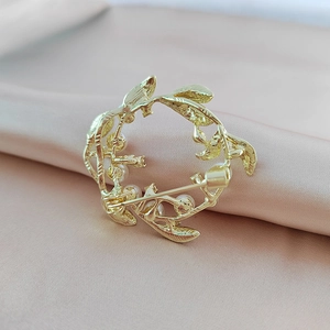 Macro detail of golden flower wreath brooch with pearls and metal texture on silk background