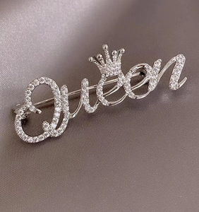 Makroaufnahme der silbernen Queen-Brosche mit Krone und funkelnden Zirkonia-Steinen