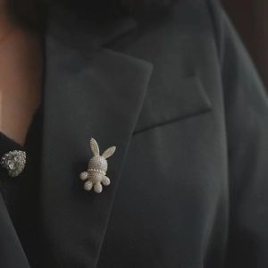 Gros plan d'une broche lapin étincelante avec strass et perles sur un revers noir