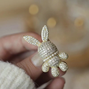 Gros plan d'une broche lapin étincelante avec collier de perles sur un pull