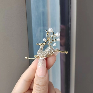 Detailed view of a gold deer brooch with sparkling rhinestones and white pearls